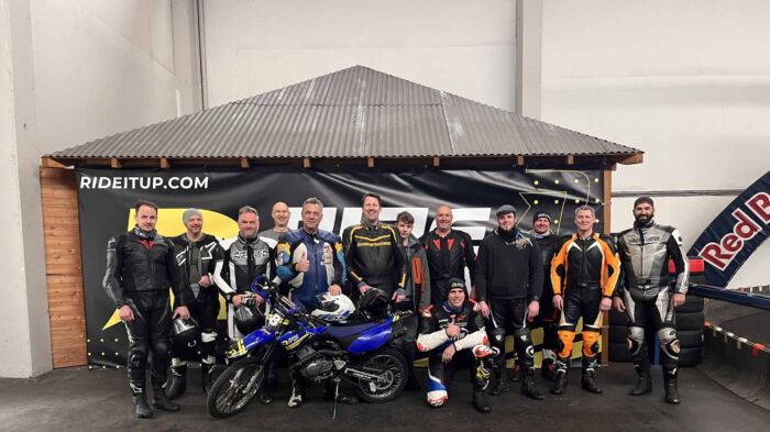 A group of people posing for a photo in front of a motorcycle.